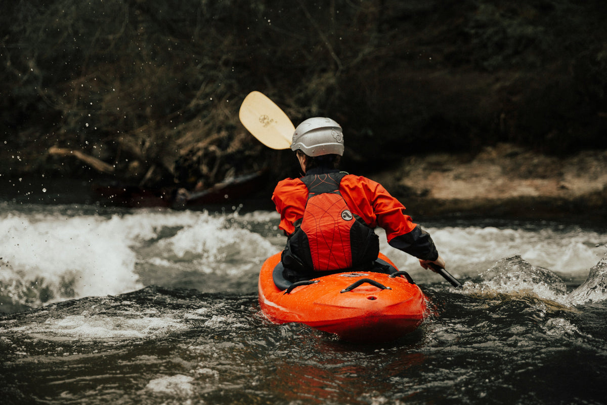 Person kayaking in a river with rocky walls